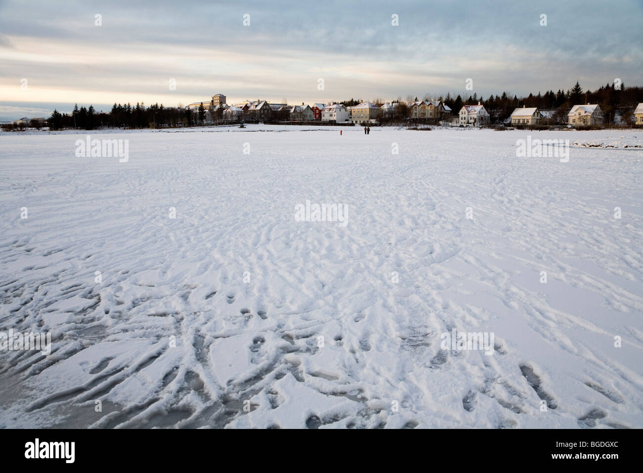 Menschen zu Fuß auf zugefrorenen See. Tjörnin-Sees, Innenstadt von Reykjavik, Island. Stockfoto