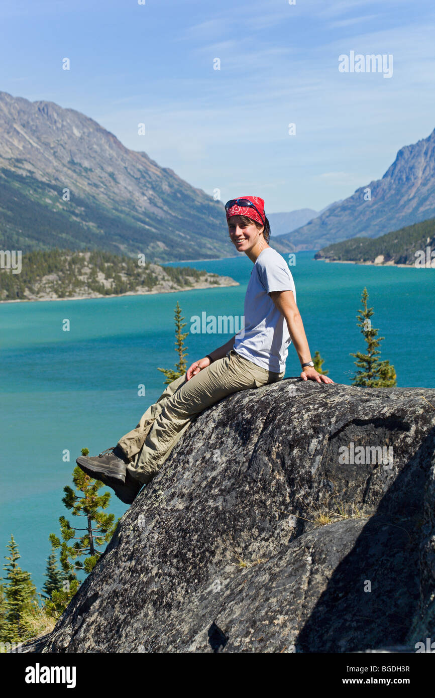 Junge Frau, Wanderer, Backpacker sitzt auf Felsen, Ruhe, Panorama, Blick auf Lake Bennett, historische Chilkoot Pass, Chi genießen Stockfoto