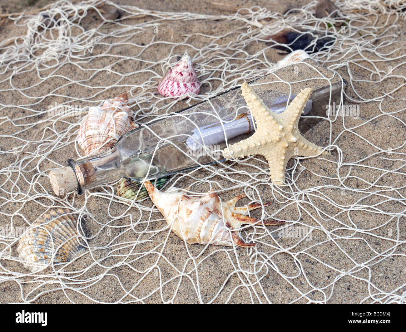 Seesterne, Muscheln und Flasche mit der Nachricht in das Fischernetz gefangen Stockfoto