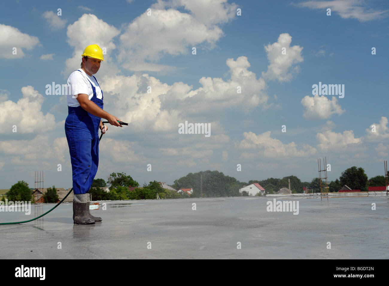 Bauarbeiter, frischen Betonplatte mit einem Schlauch Bewässerung Stockfoto