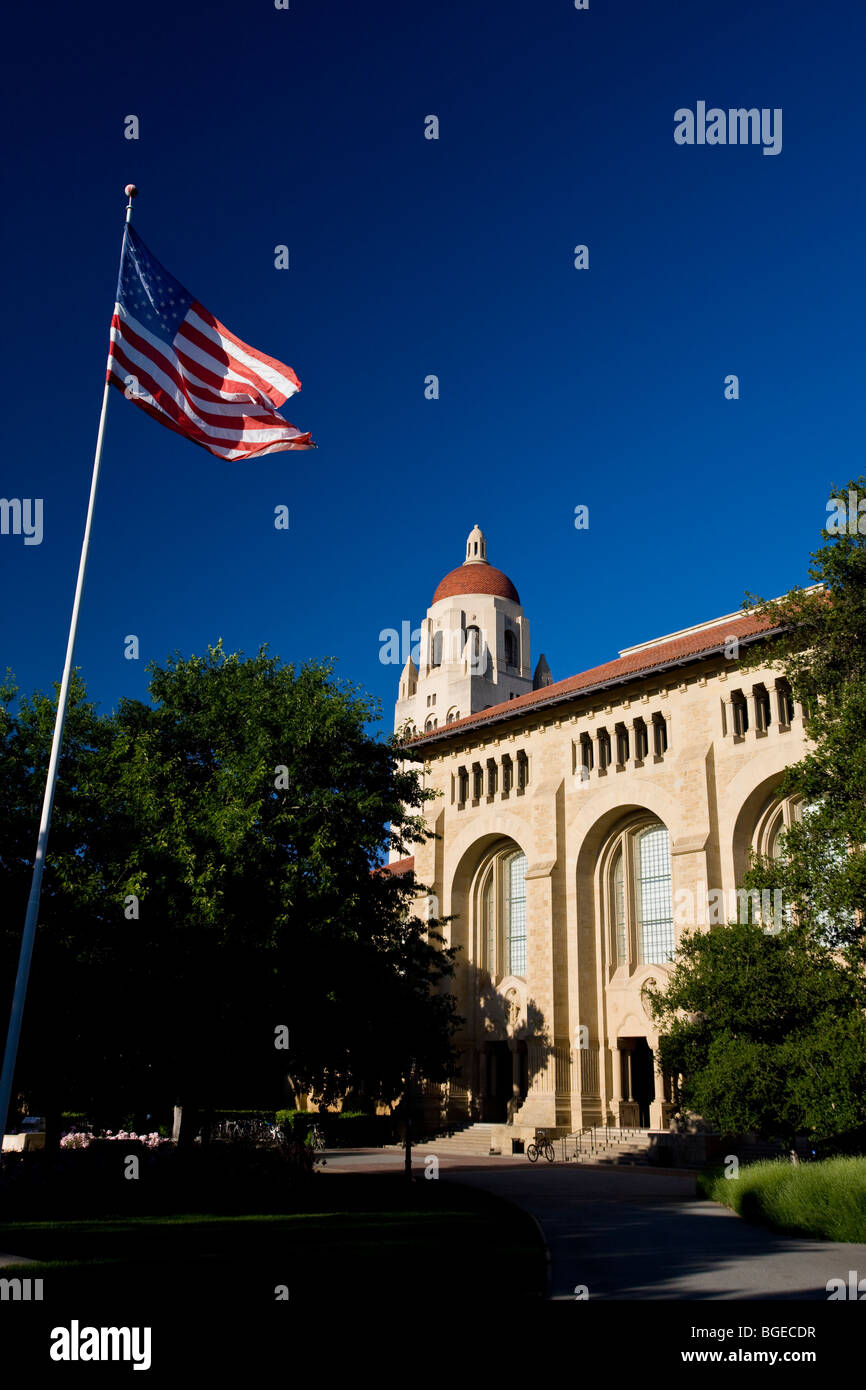 Der Hoover Tower steht hinter einer amerikanischen Flagge an der Stanford University, an einem klaren Tag mit blauem Himmel, Stanford, Kalifornien, USA. Stockfoto