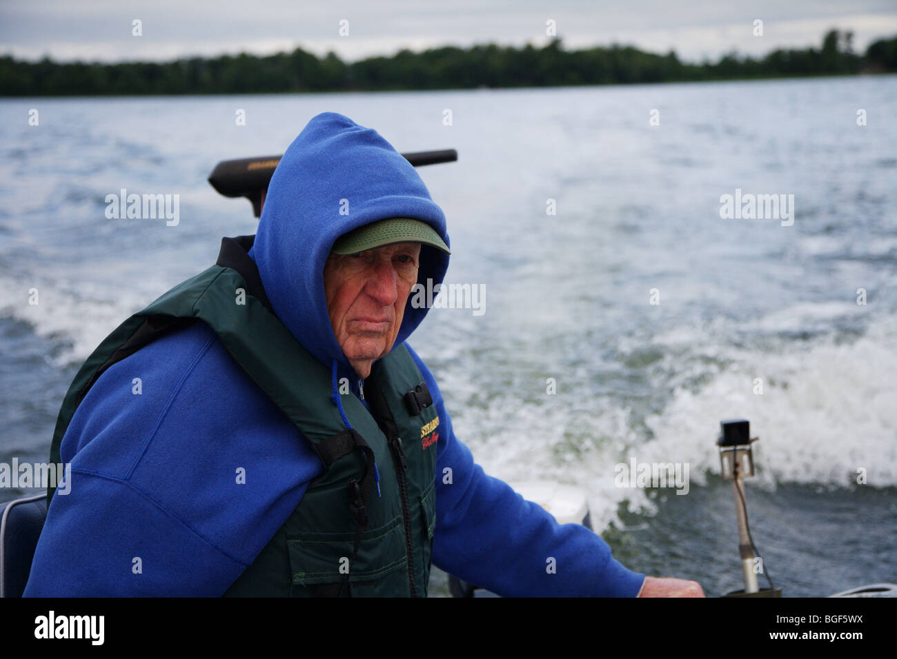 Senior ältere erfahrene Angelführer fahren Alumnacraft Fischerboot im nasskalten Wetters kabbeliges Wasser Gefolge Wellen Aktion Stockfoto