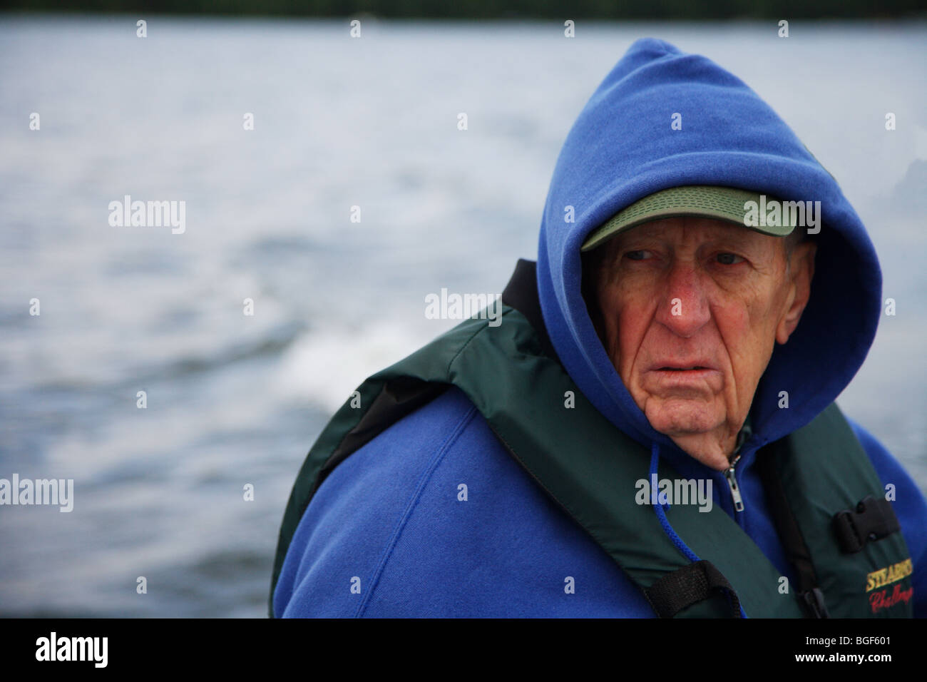 Senior ältere erfahrene Angelführer fahren Alumnacraft Fischerboot im nasskalten Wetters kabbeliges Wasser Gefolge Wellen Aktion Stockfoto