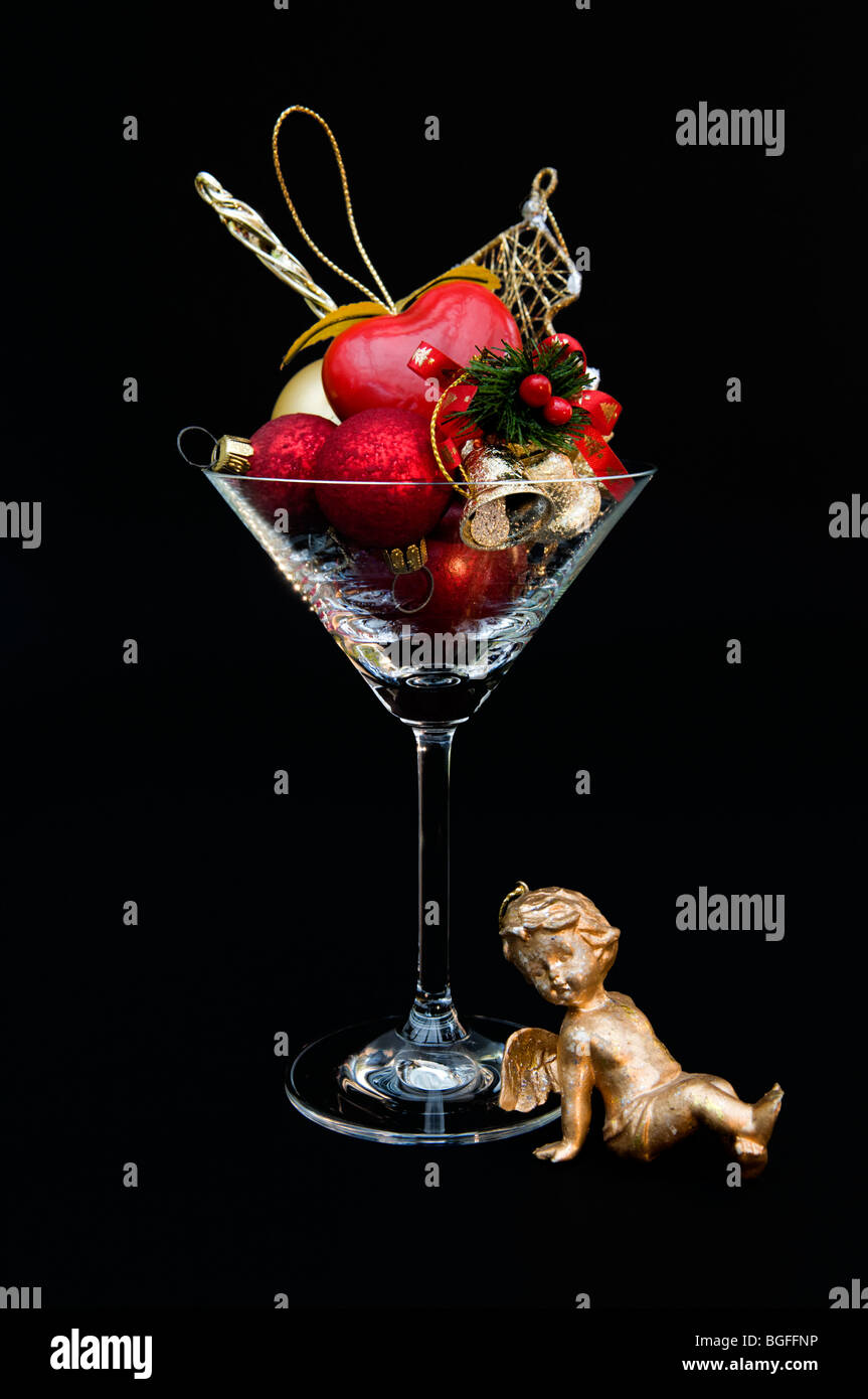 Rot und gold Weihnachtsschmuck im Cocktailglas vor schwarzem Hintergrund Stockfoto