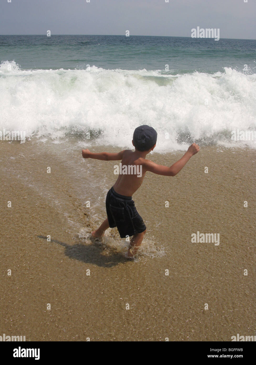 Ein kleiner Junge am Rande der Strand Wasserwellen Stockfoto