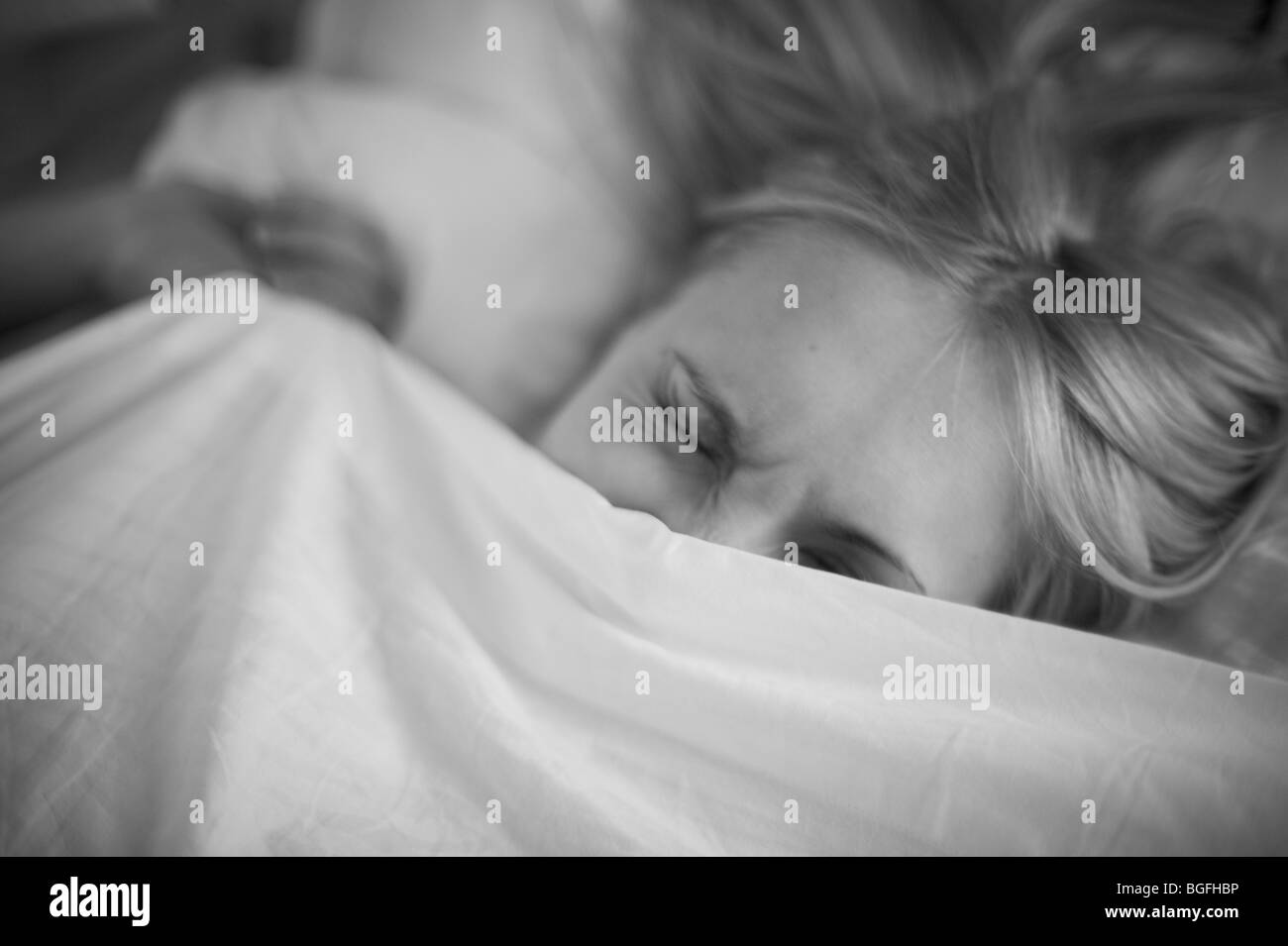 Frau im Bett unter Decke kriechend Stockfoto