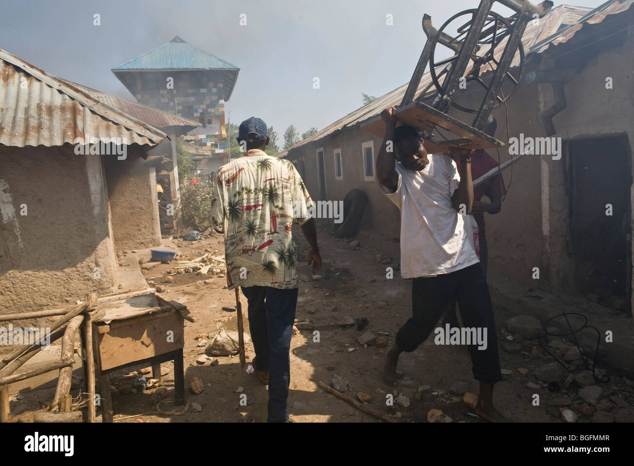 Plünderer stehlen Möbel aus brennenden Häusern in einer Nachbarschaft in Kisumu, Kenia während Gewalt das Land nach den Wahlen. Stockfoto