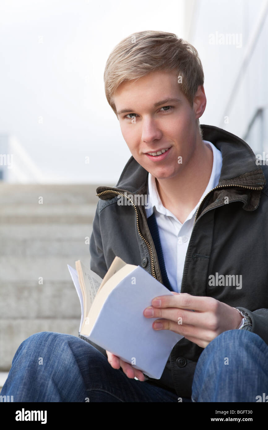 Junge fröhlich hübscher Mann hält ein Buch mit Blindabdeckung Stockfoto