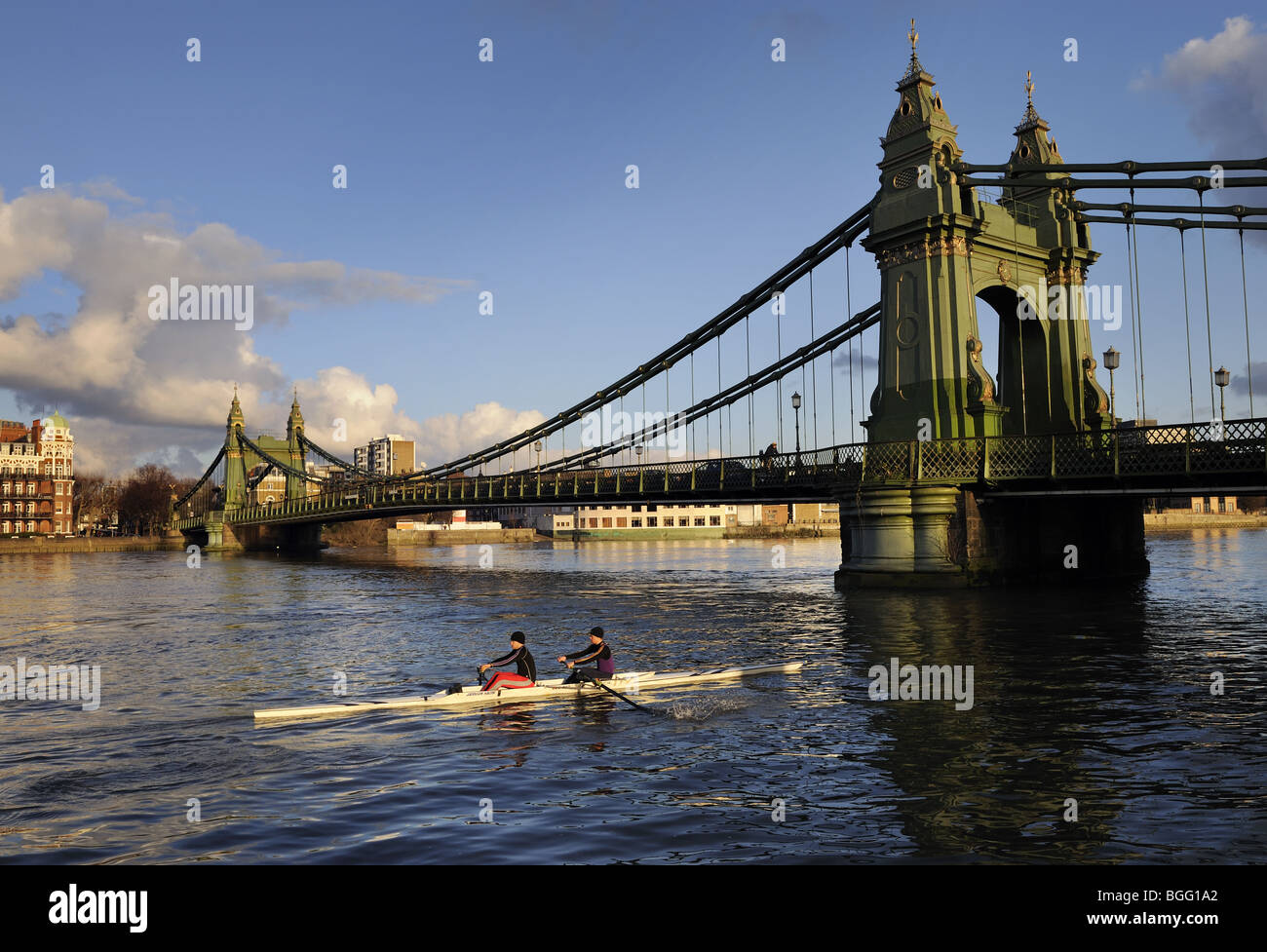Ruderer vorbei unter Hammersmith Hängebrücke, Themse, London, an einem Wintertag Stockfoto