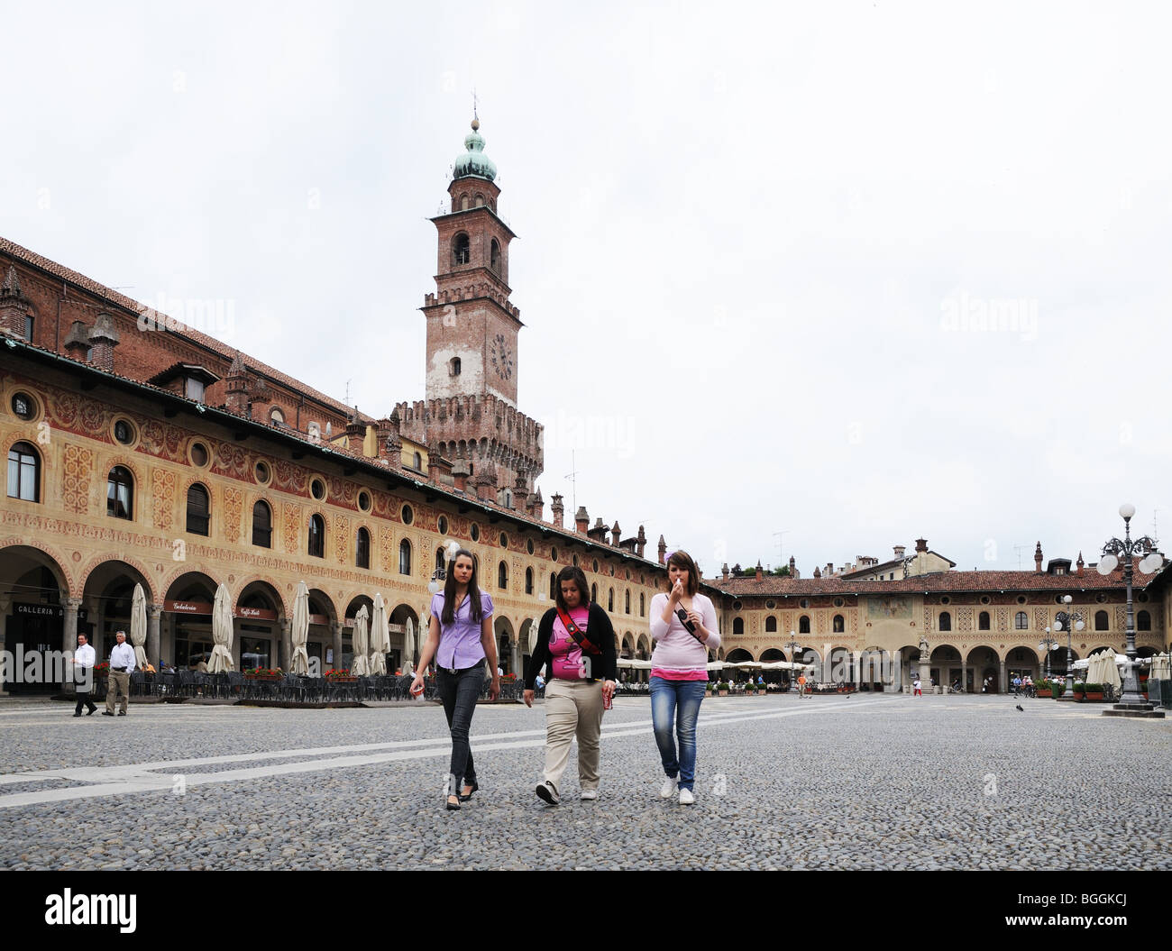 Junge Frauen mit Bramante Turm im Castello Sforzesco in Piazza Ducale Vigevano Lombardei Italien mit Arkaden oder portaci Stockfoto
