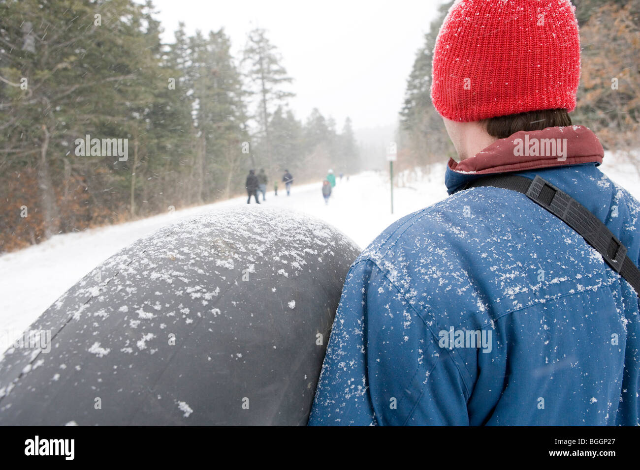 Ein Mann hält ein Innenrohr, immer bereit, sich ein Rodelhang Schläuche gehen winter, New Mexico, Sandia Berge. Stockfoto