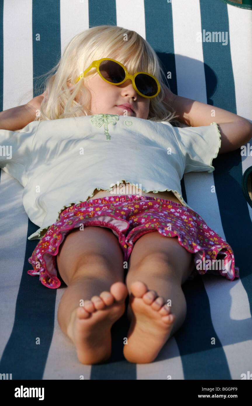 Stock Foto von einem 4-jährigen Mädchen mit Sonnenbrille auf dem Liegestuhl liegen. Stockfoto