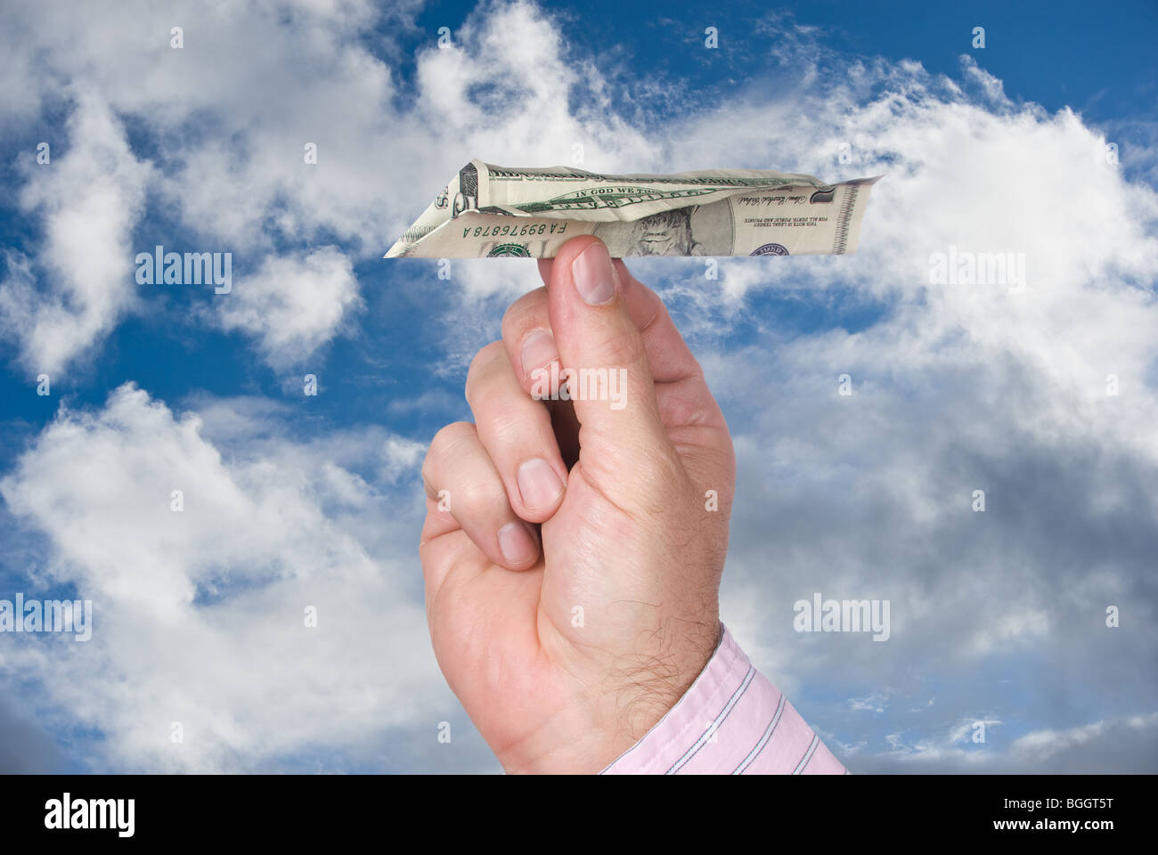 Ein Mann wirft einen Flieger, der einen fünf-Dollar-Schein in ein blauer Himmel mit weißen, geschwollenen Wolken gemacht. Stockfoto