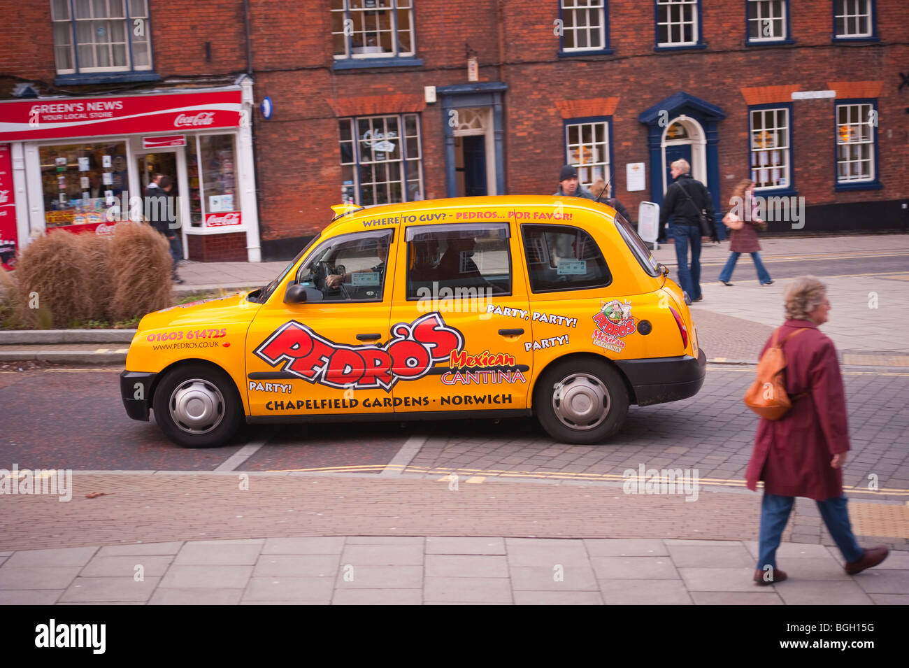 Ein gelbes Taxi fährt durch die Stadt und zeigt Bewegung in Norwich, Norfolk, Großbritannien Stockfoto