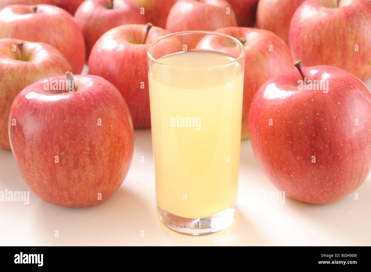 Glas Apfelsaft unter Äpfel Stockfoto