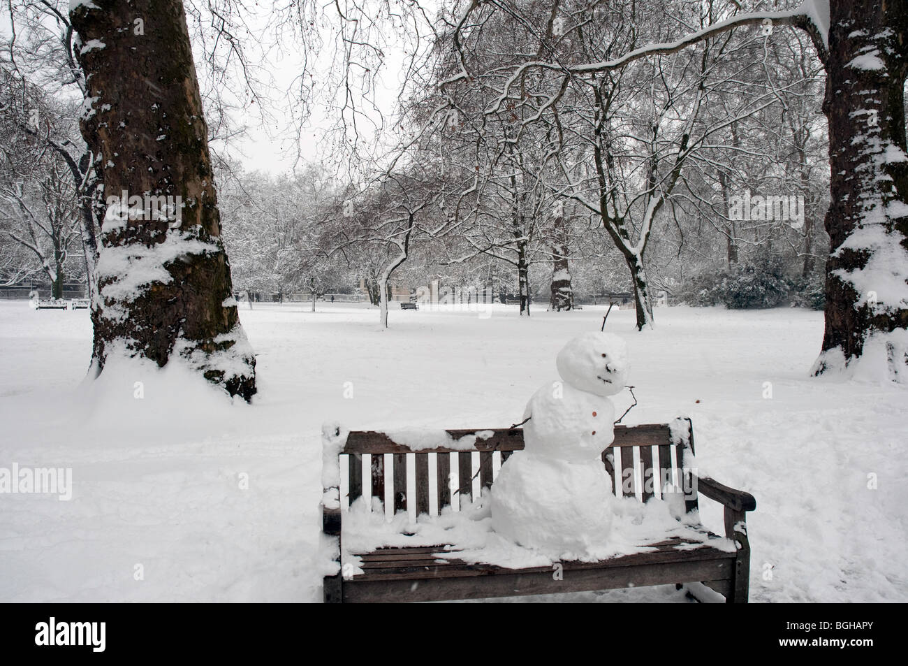Bank mit Schneemann in St James Park im Zentrum von London im Schnee Stockfoto