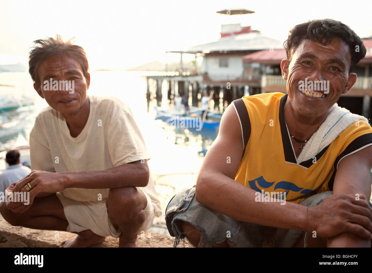 Zwei philippinische Männer hocken und lächelnd Coron Markt; Coron Town; Busuanga Island; Philippinen Stockfoto