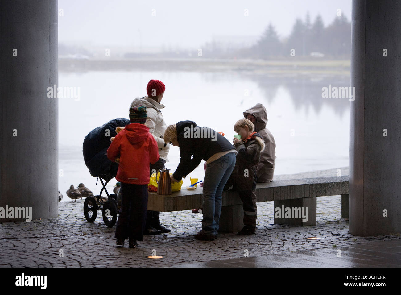 Eine Familie, genießen ein Picknick draußen regnerisch, neblig tagsüber. Rathaus von Reykjavik, Innenstadt von Reykjavik, Island. Stockfoto
