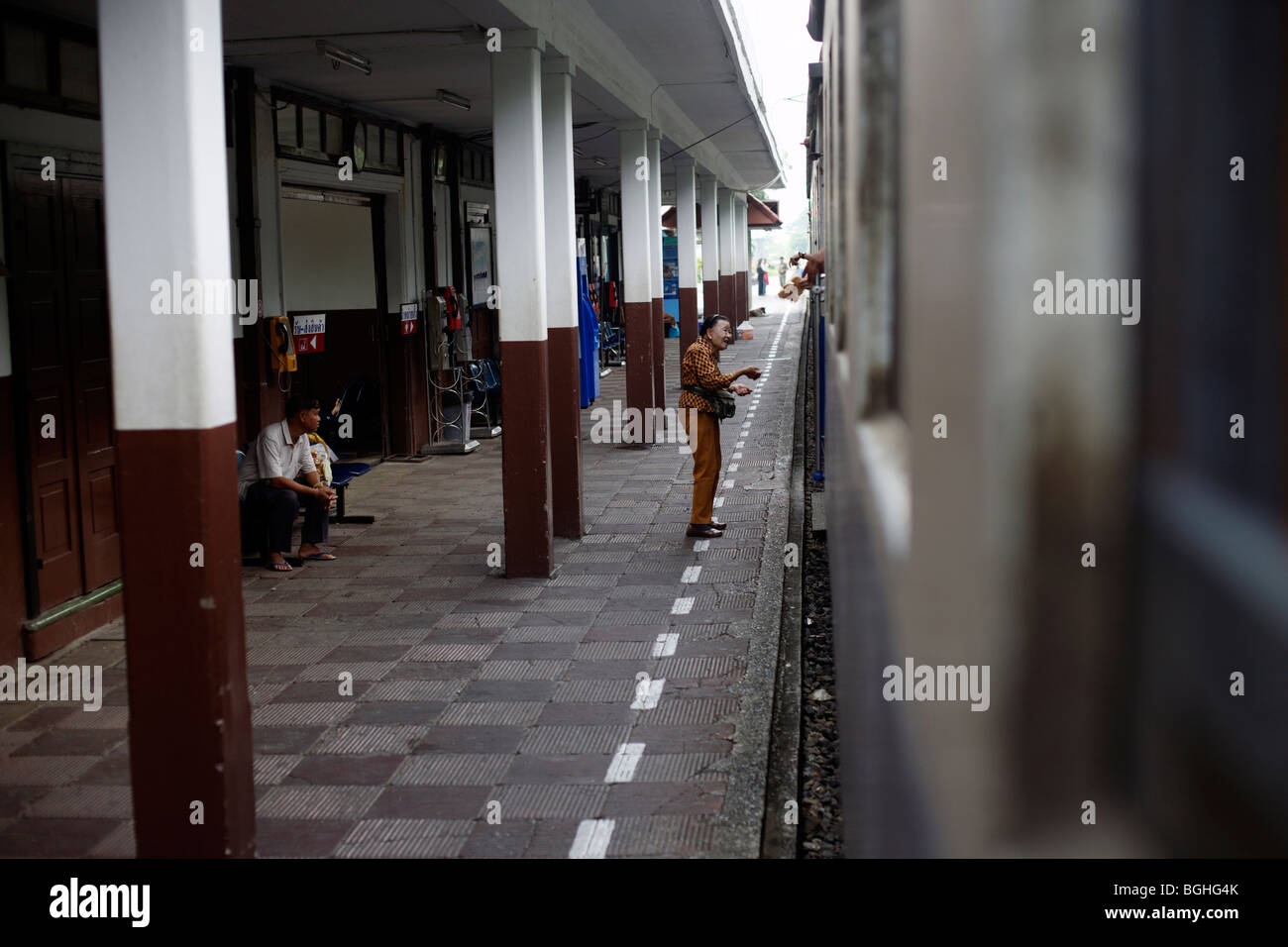 Eine Frau verkauft Lebensmittel aus dem Bahnsteig mit einem Passagier auf einem Zug in Thailand Stockfoto
