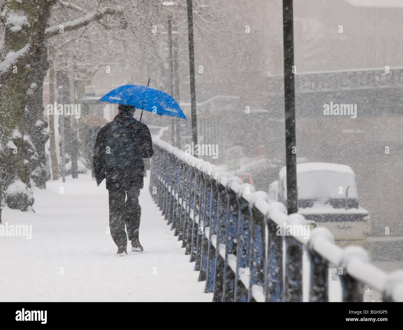 MANN MIT REGENSCHIRM IM SCHNEE ZU FUß AUF BÜRGERSTEIG RIVERSIDE ROAD NORWICH NORFOLK EAST ANGLIA ENGLAND UK Stockfoto