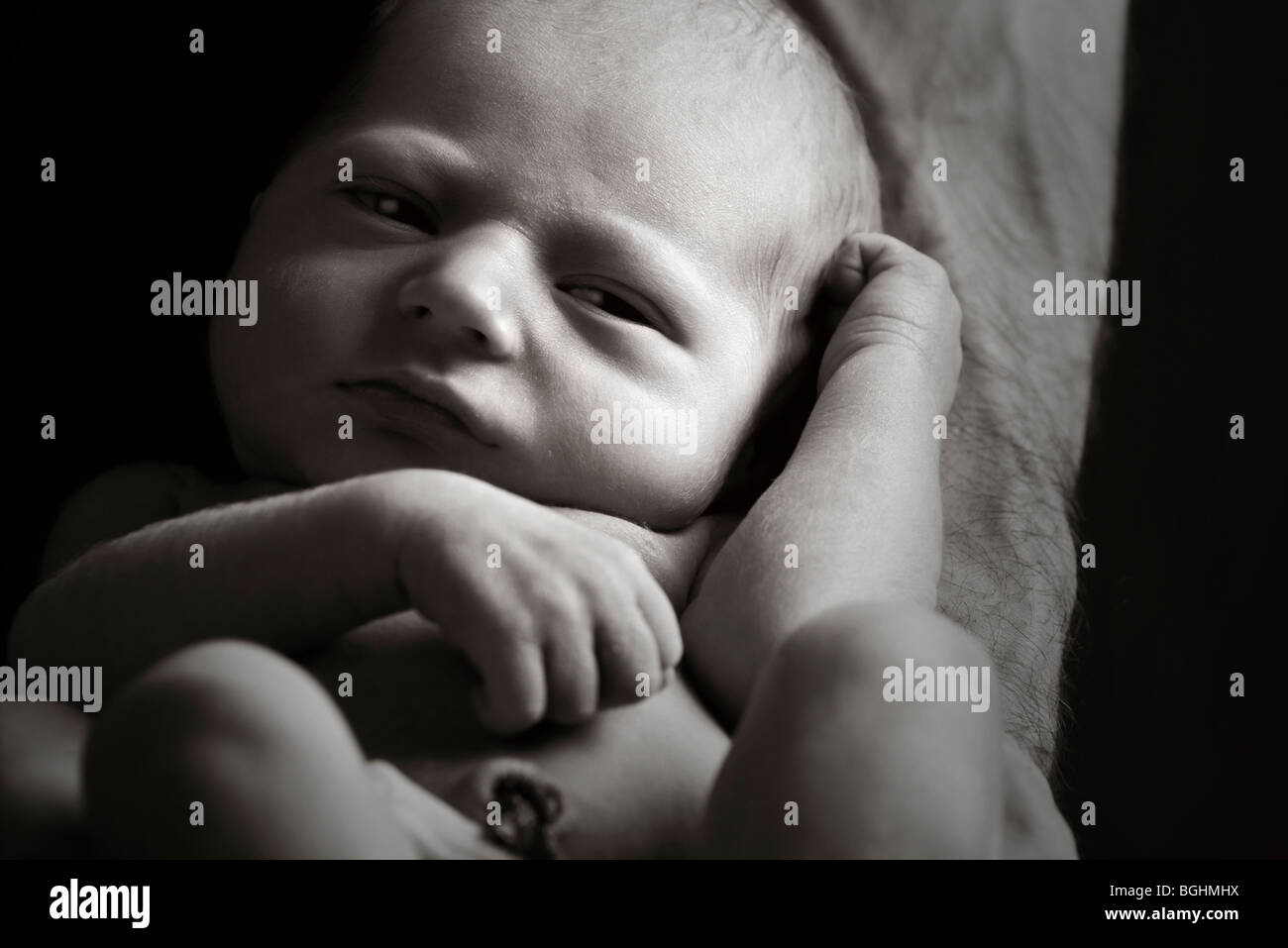 Schöne Low Key Aufnahme eines Neugeborenen auf seines Vaters Arm Stockfoto