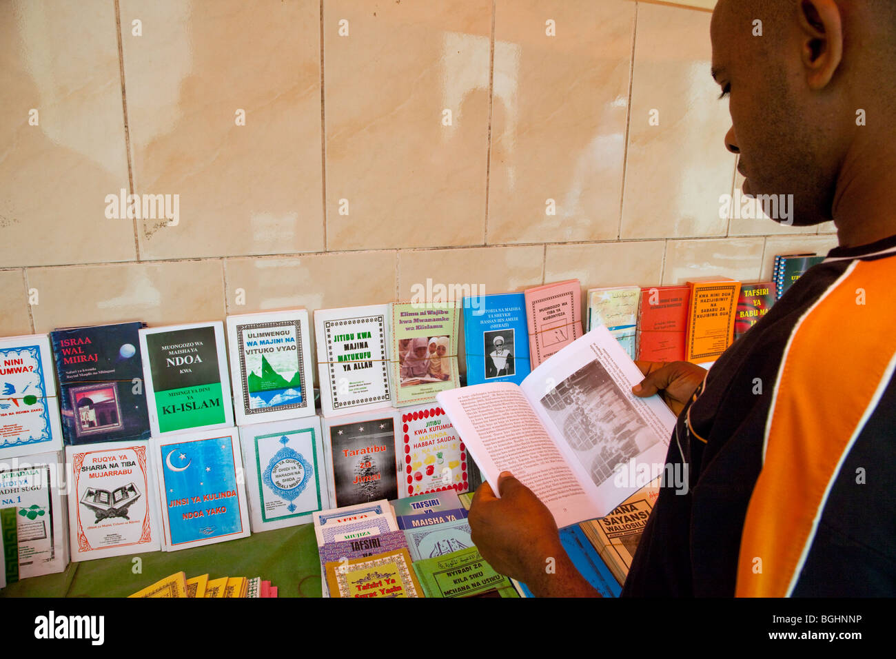 Sansibar, Tansania.  Kunden wird ein Buch in einem Buchständer, Verkauf von Büchern über den Islam in Swahili oder Arabisch untersucht. Stockfoto