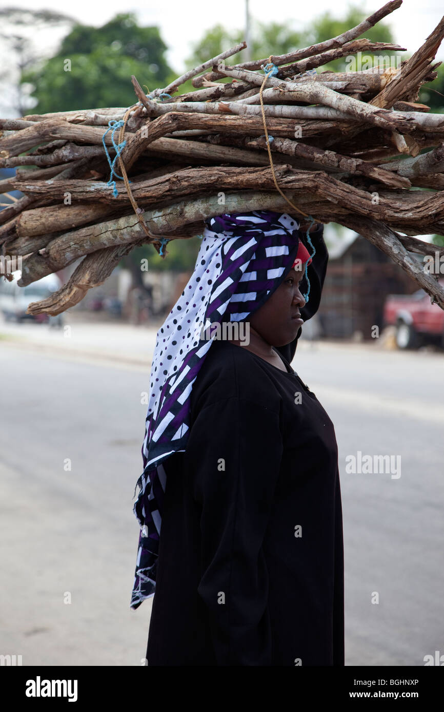 Sansibar, Tansania. Dame mit Brennholz auf Kopf. Stockfoto