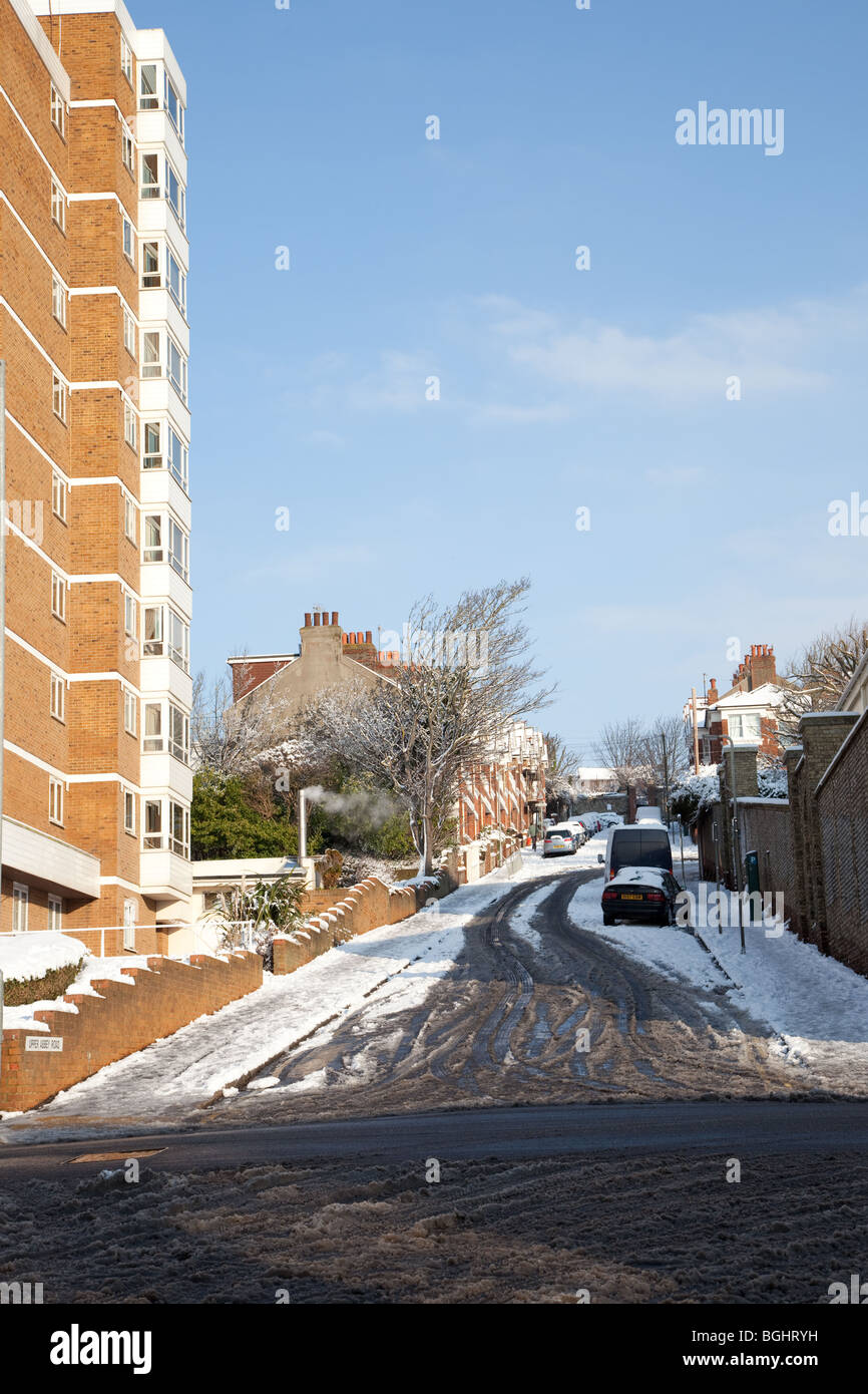 Schneebedeckte Straße in Brighton mit Glatteis und Schnee bedeckten Autos und Bürgersteige zusammen mit Matsch bedeckt Straßen. Stockfoto