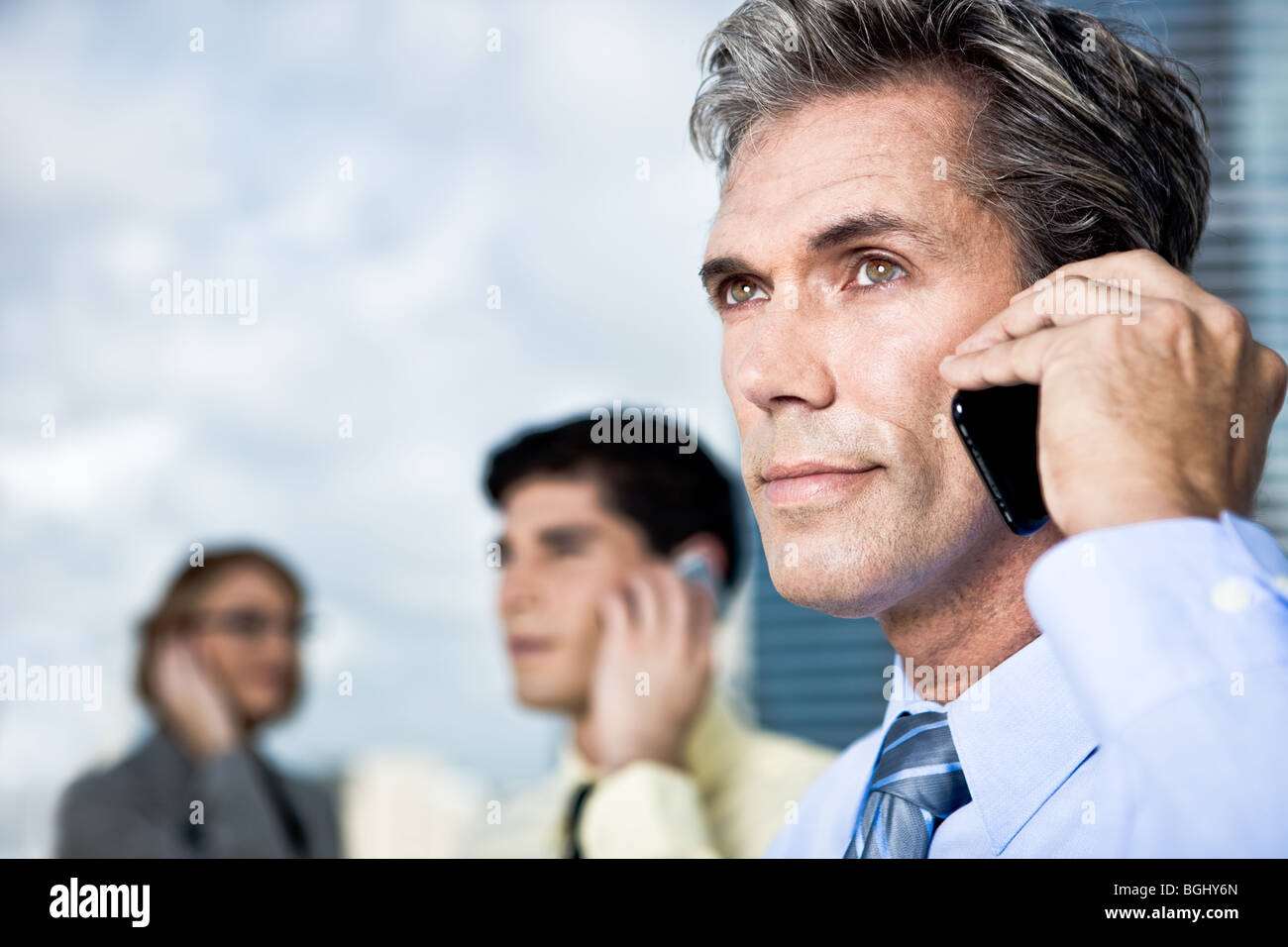 Ein reifer Geschäftsmann und sein Team sprechen auf dem Handy außerhalb Stockfoto