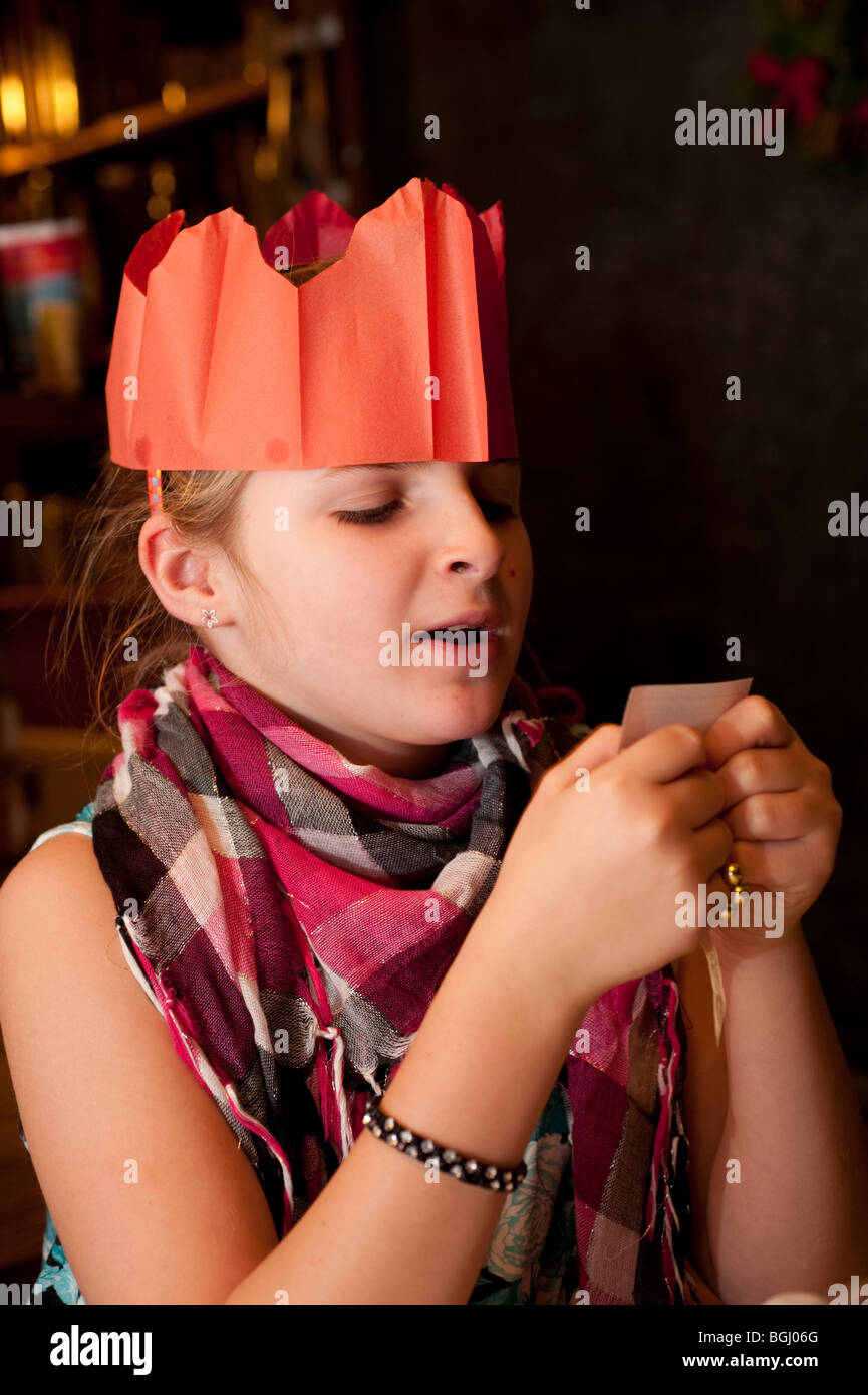 Kind trägt ein Papier Partyhut lesen einen Witz von einem Christmas cracker Stockfoto