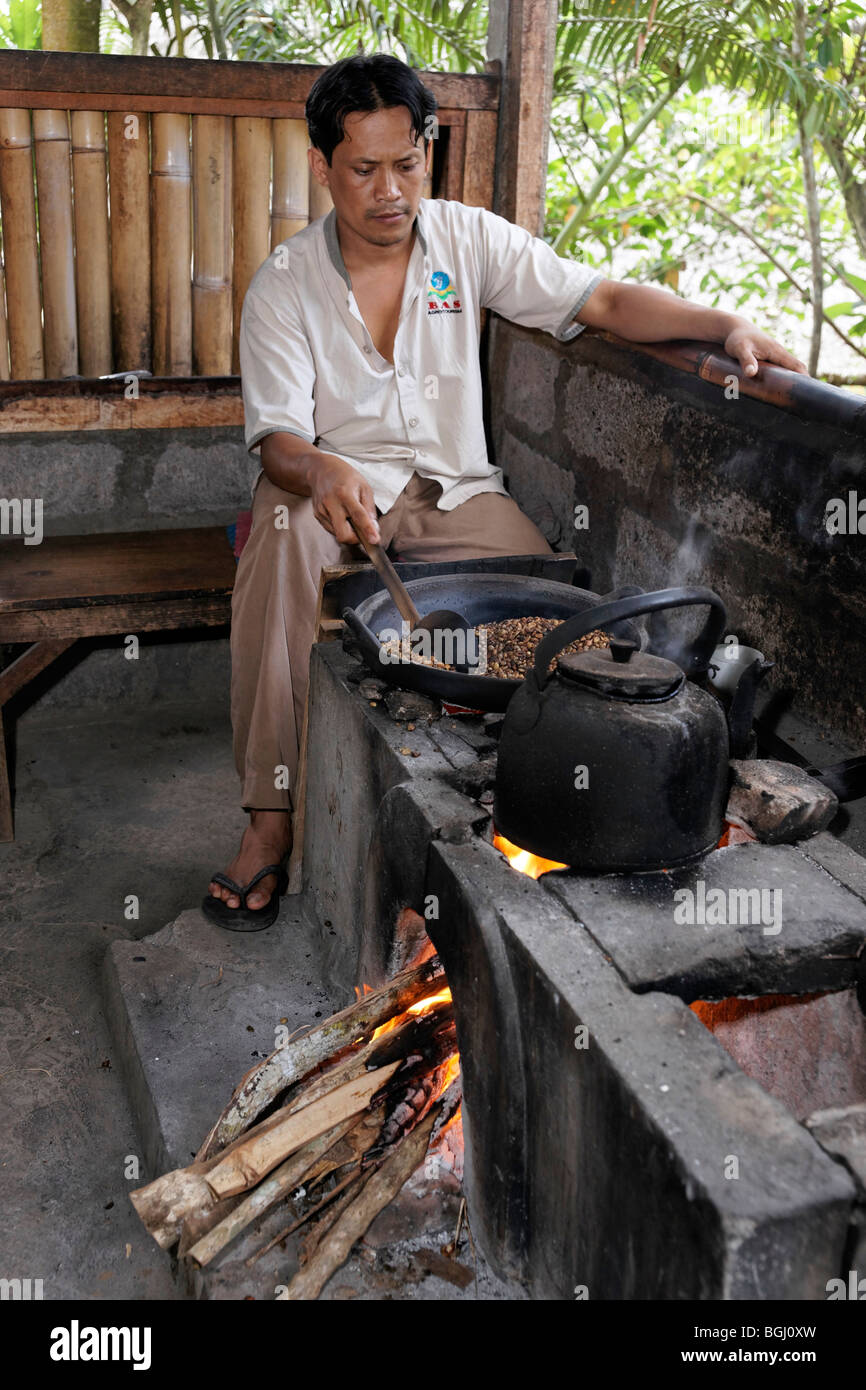 Balinesische Mann rösten Kaffee Bohnen. Schwerpunkt ist die Bohnen in der Pfanne. Stockfoto