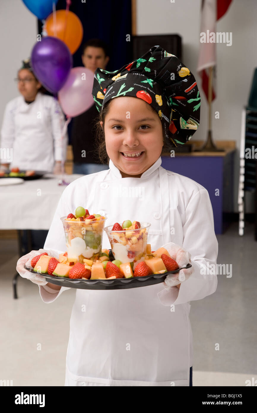 Bei einem Kochwettbewerb, eine Latina 3. Grader hält das Gericht sie vorbereitet hat, eine Platte mit Obst und Joghurt Regenbogen. Stockfoto