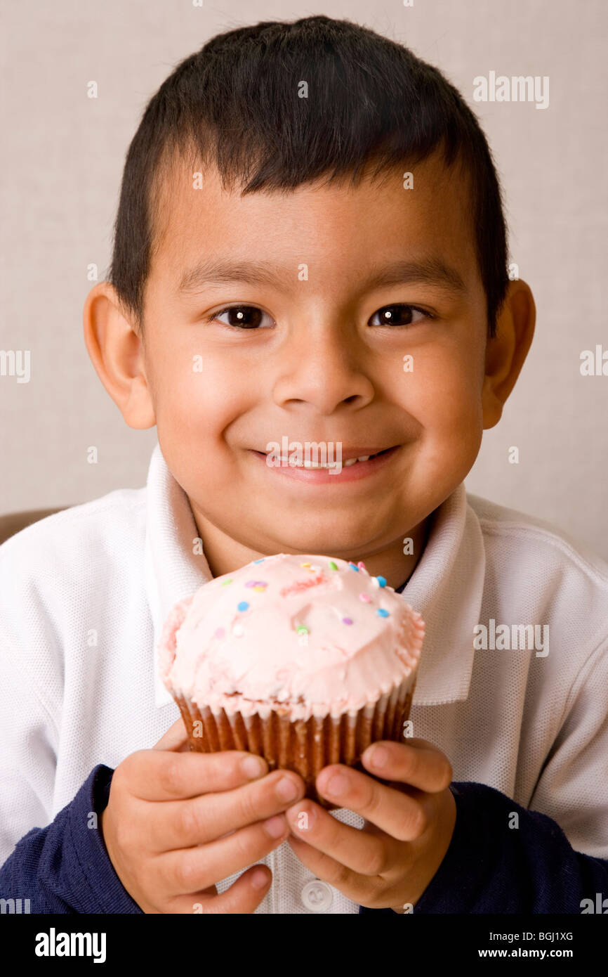 Latein 5 Jahre alten Jungen feiern Valentinstag. Halten einen rosa Valentine Cupcake. Stockfoto
