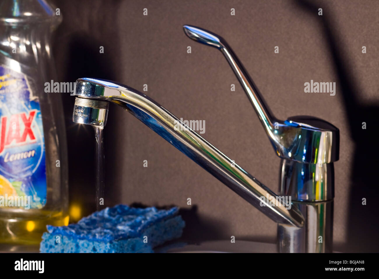 Tropfenden Wasserhahn in der Küche mit Geschirrspülmittel flüssig und blauen Schwamm. Stockfoto