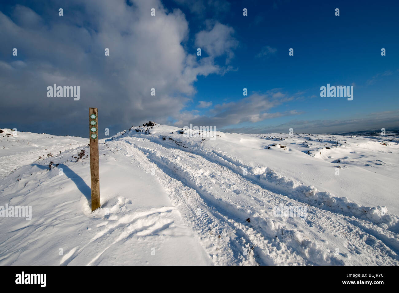 Fahrzeugspuren auf Maultierweg und Wanderweg gerichtete Wegweiser auf Moorland im winter Stockfoto
