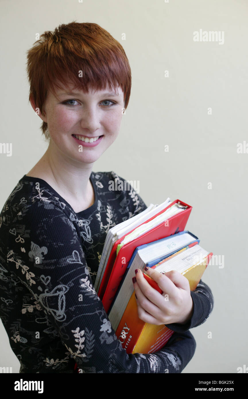Teen Mädchen hält einen Stapel Bücher in der Schule Stockfoto