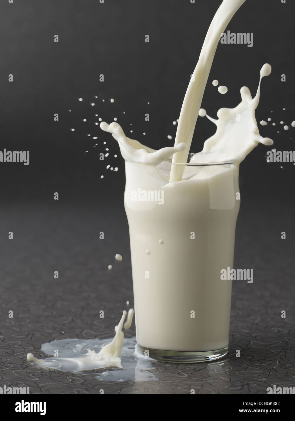 Milch auf grauem Hintergrund in Glas gießen Stockfoto