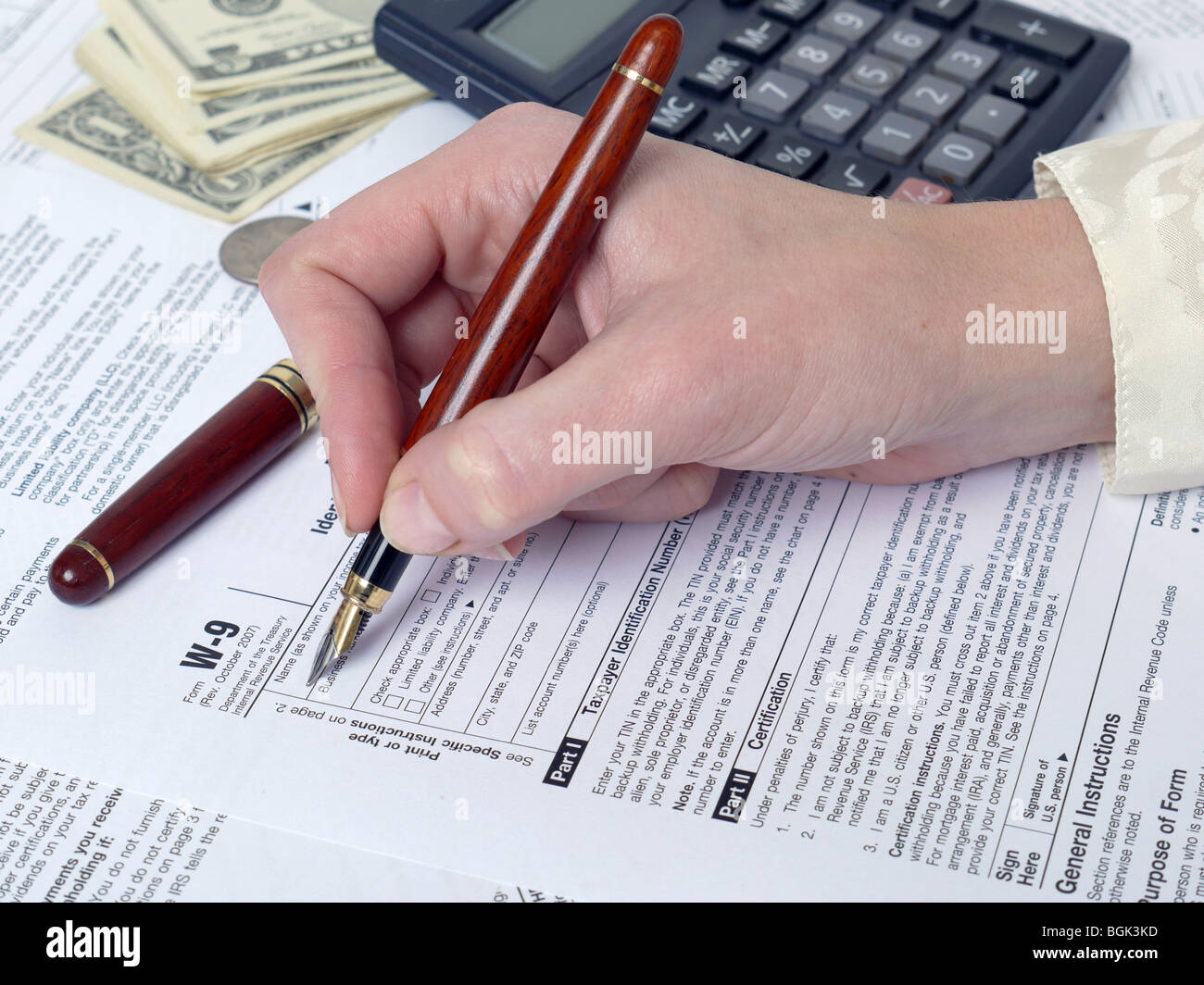 Weibliche Hand Ausfüllen der Einkommensteuererklärung des w-9 mit Stift Stockfoto