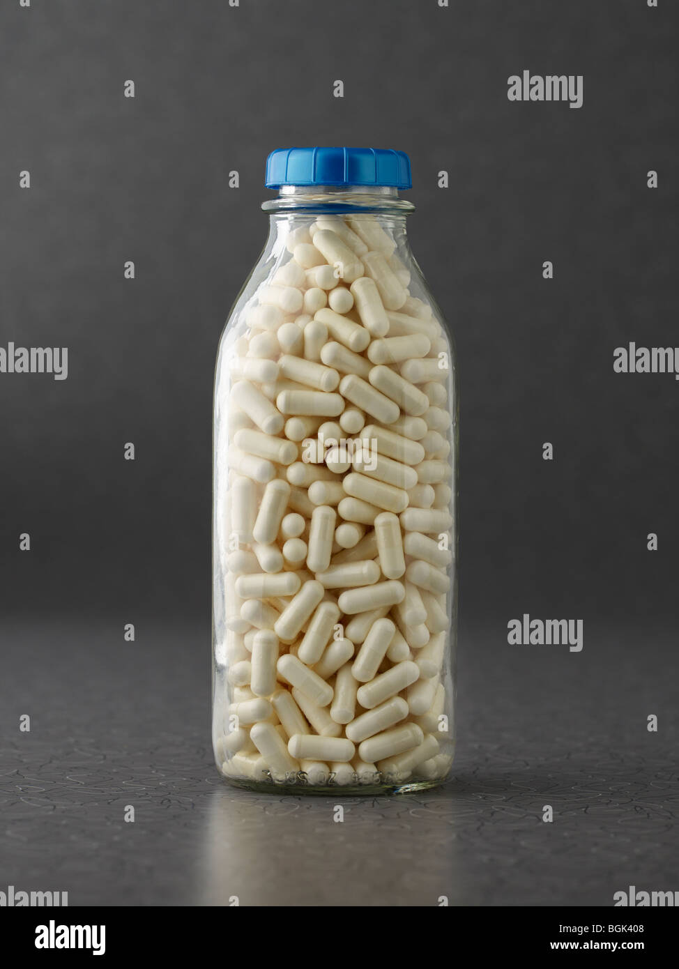 Milch-Protein-Kapseln in Milchflasche auf grauem Hintergrund Stockfoto