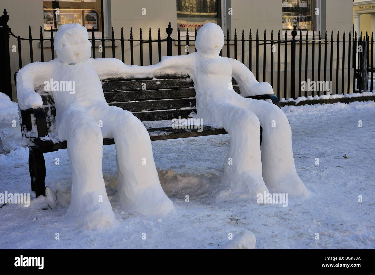 Schneeskulpturen sitzen auf einer Bank Stockfoto