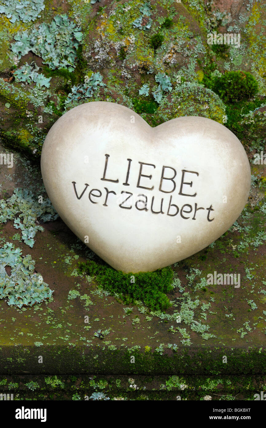 Herz aus Stein mit den Worten "Liebe Verzaubert", Deutsch für "Liebe verzaubert" Stockfoto