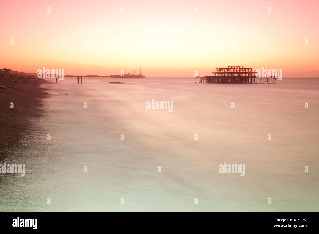 Brighton Pier und Brighton Pier West kurz vor Sonnenaufgang mit dem Meer verwischt durch Verwenden von Filtern. Ein roter und gelber Himmel gesehen Stockfoto