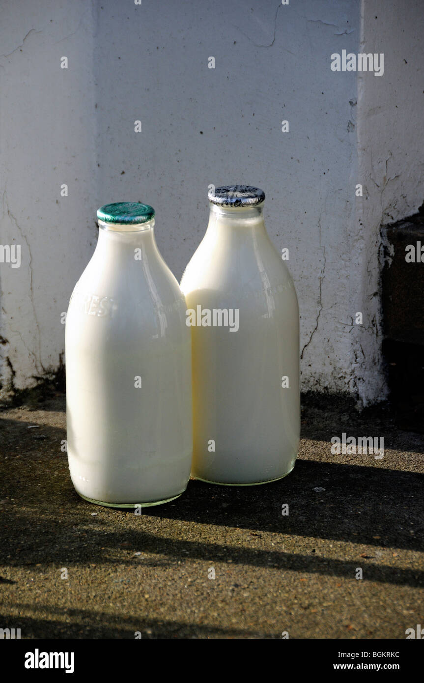 Zwei volle Pint Flaschen Milch vor der Haustür, eine grüne Oberseite und eine silberne Null Abfall Stockfoto