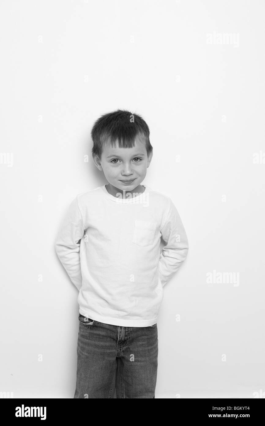 Kleiner Junge steht durch die Wand in schwarz / weiß Stockfoto