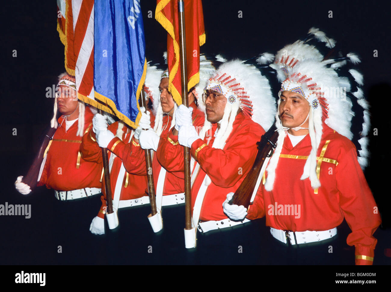 Bewaffnete Farbschützer, die mit traditionellen Federkopfschmuck bekleidet sind, tragen während des Grand Entry beim Red Earth Indian Festival und Pow Wow, Oklahoma, Flaggen Stockfoto