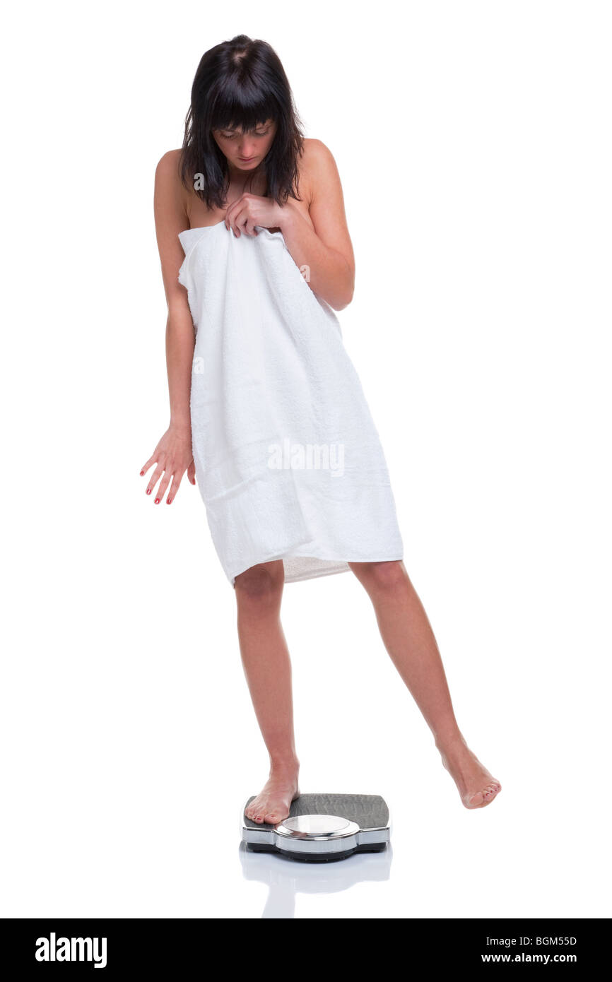 Eine Frau in ein Handtuch mit einem Gewicht von selbst gewickelt und versuchen zu betrügen die Waage, isoliert auf weißem Hintergrund. Stockfoto