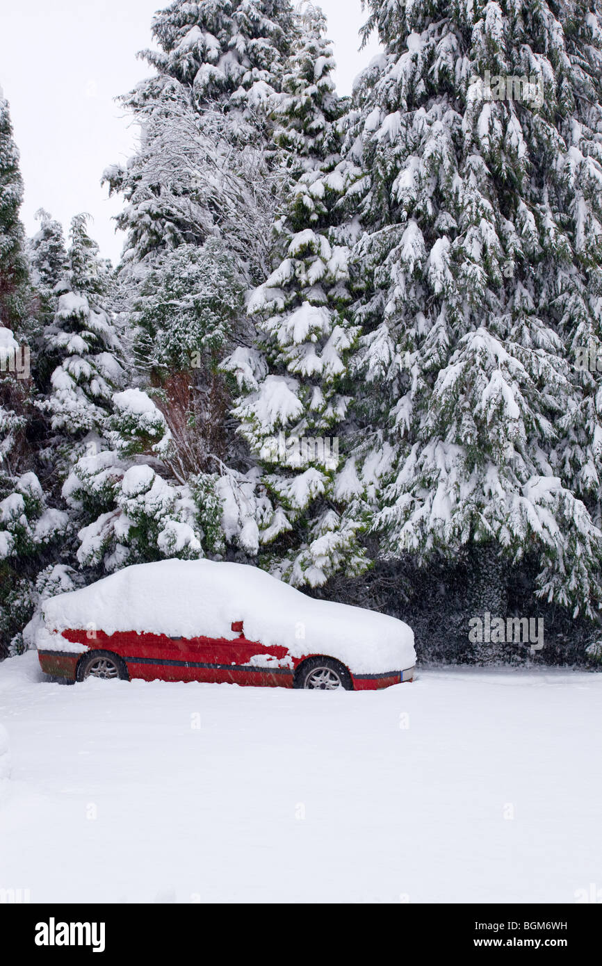 Ein verlassenes rote Auto nach einem letzten Schneesturm im Schnee bedeckt. Stockfoto