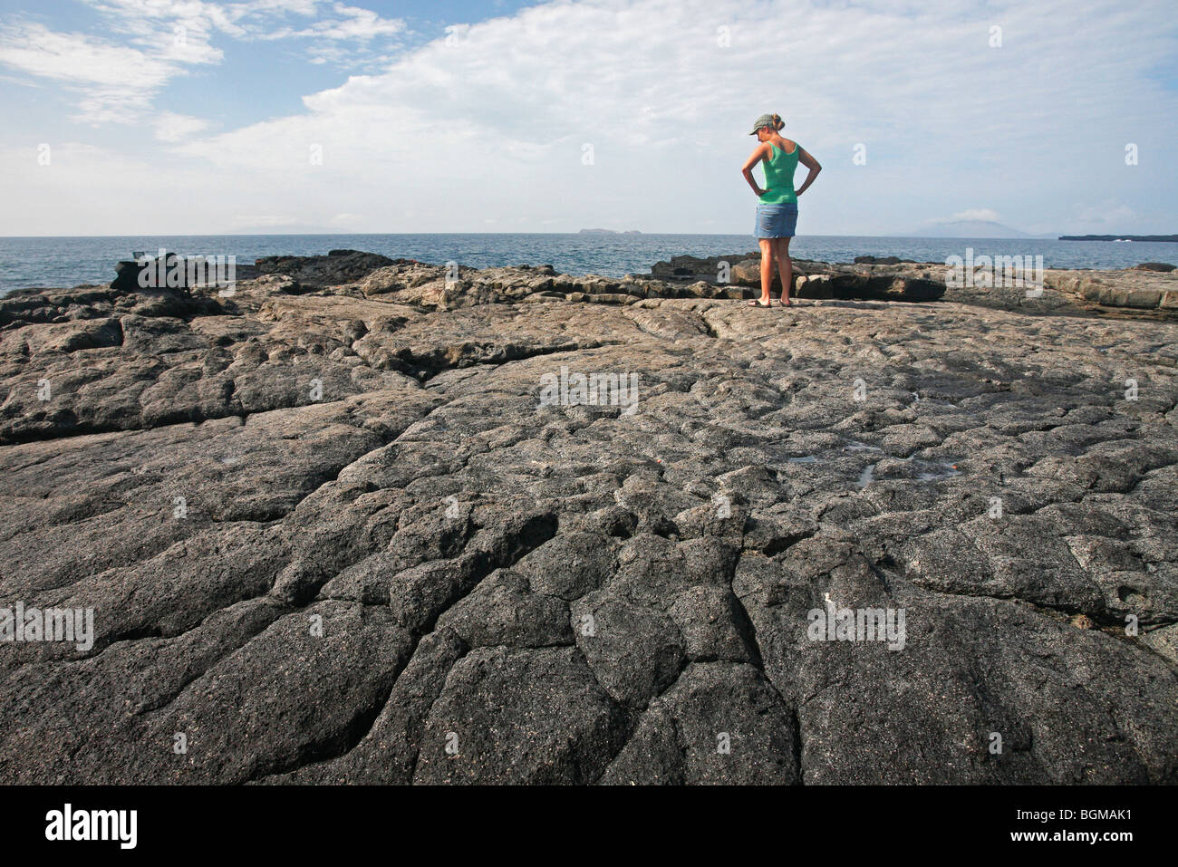 Touristen stehen auf erstarrter Lava Blick auf das Meer bei Sombrero Chino / Chinaman Hut, Insel Santiago, Galápagos-Inseln Stockfoto Touristen stehen auf erstarrter Lava Blick auf das Meer bei Sombrero Chino / Chinaman Hut, Insel Santiago, Galápagos-Inseln Stockfoto