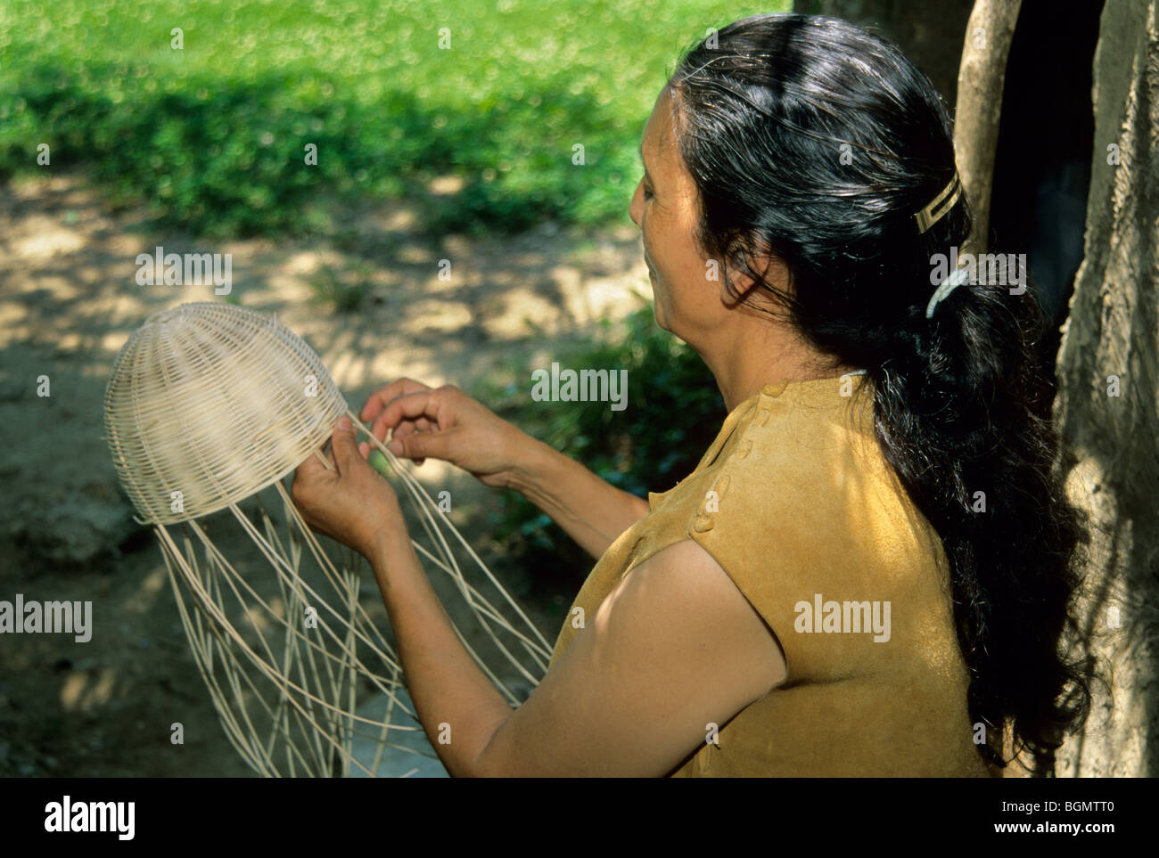 Cherokee-Frau in traditioneller Hirtenhaut-Kleidung demonstriert die Korbweberei im Cherokee Indian Village in Tahlequah Oklahoma Stockfoto