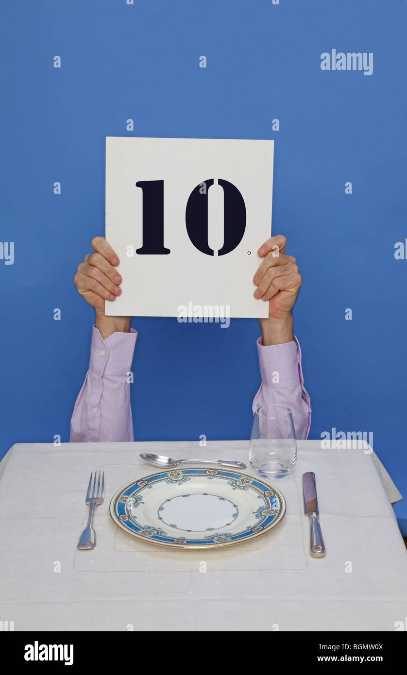 Mann am Tisch Essen hält 10 Zeichen zum Preis Essen Stockfoto